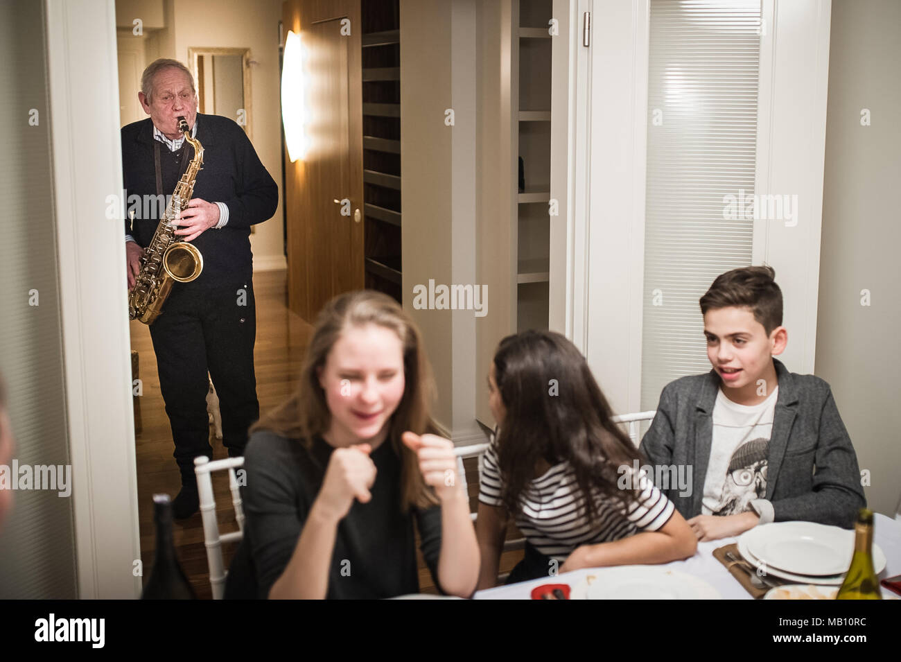 Nonno suonare il sassofono durante la cena di famiglia; le diverse generazioni Foto Stock
