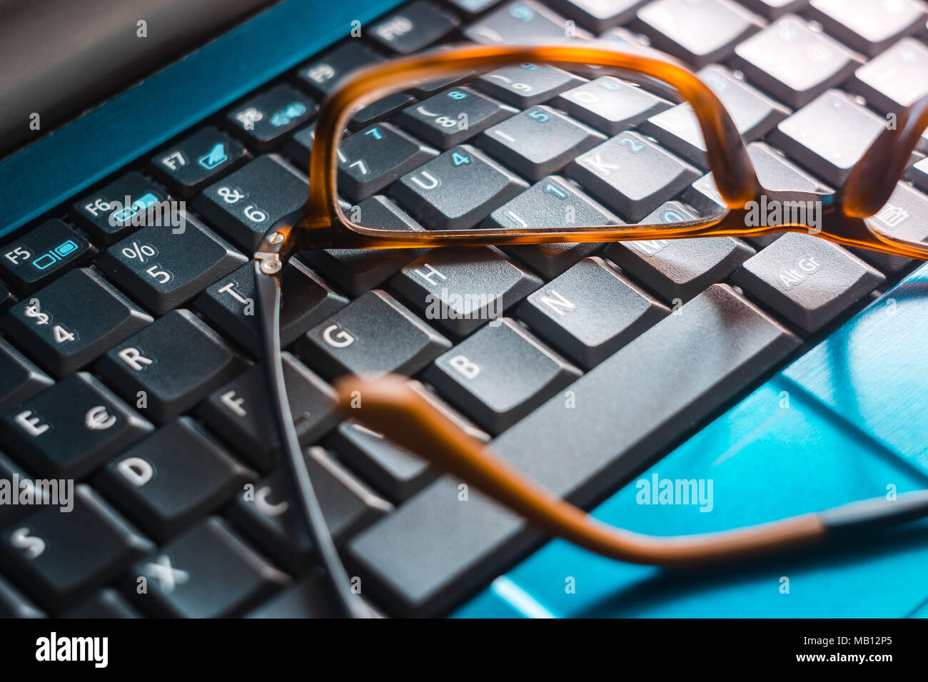 Un paio di occhiali posti sulla tastiera di un computer Foto Stock
