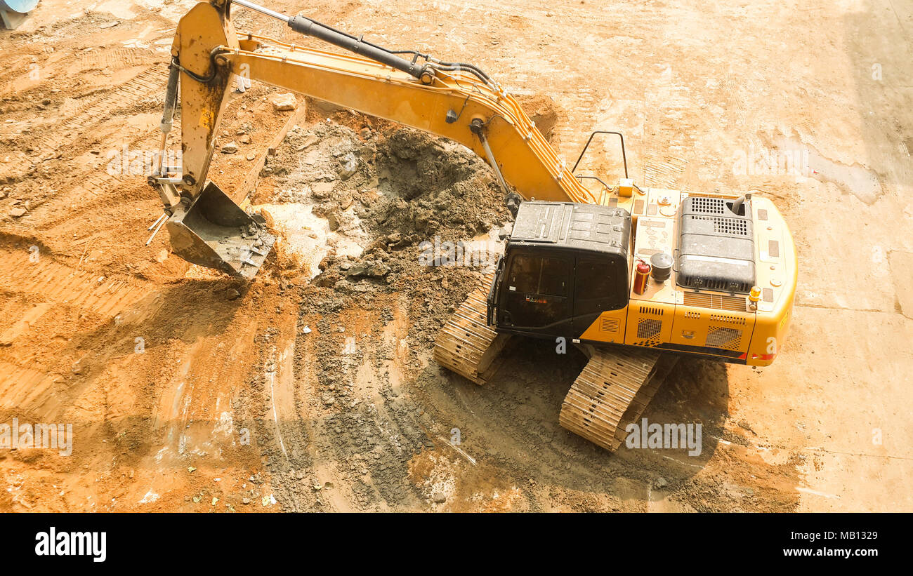 Vista aerea di escavatore cingolato inizia a scavare la preparazione di terra per costruire un condominio. via hoe funzionante. La preparazione del sito prima di costruire un condominio Foto Stock