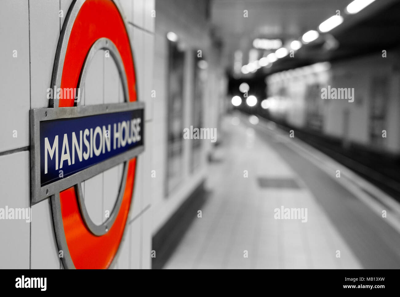 25 Marzo 2018 - Londra, Inghilterra. La metropolitana di Londra la stazione della metropolitana Mansion House roundel segno sulla piattaforma. In treno in background. Foto Stock