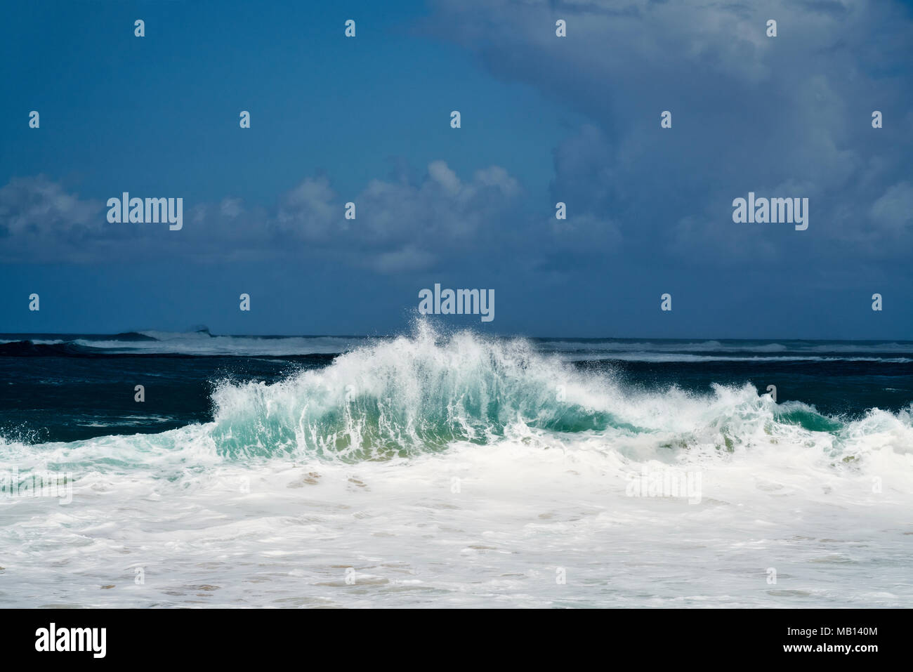 La luce del sole illumina momento onda di arricciatura lungo la costa nord di Ha'ena sulla spiaggia Hawaii Isola di Kauai. Foto Stock