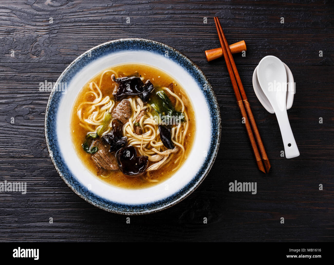 Frumento asiatici Ramen noodle con carne di manzo, legno di funghi e di cavolo cinese cavolo in ciotola di legno scuro dello sfondo Foto Stock