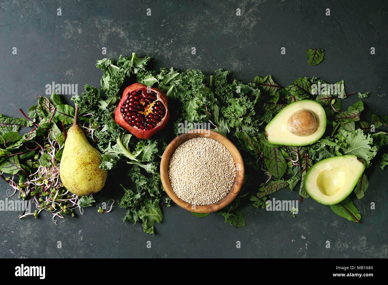 Insalata verde e frutta mix per insalata di cavolo riccio, giovani foglie di bietola, germogli, pera, avocado, melograno, ciotola di materie non cotti quinoa oltre il testo scuro Foto Stock
