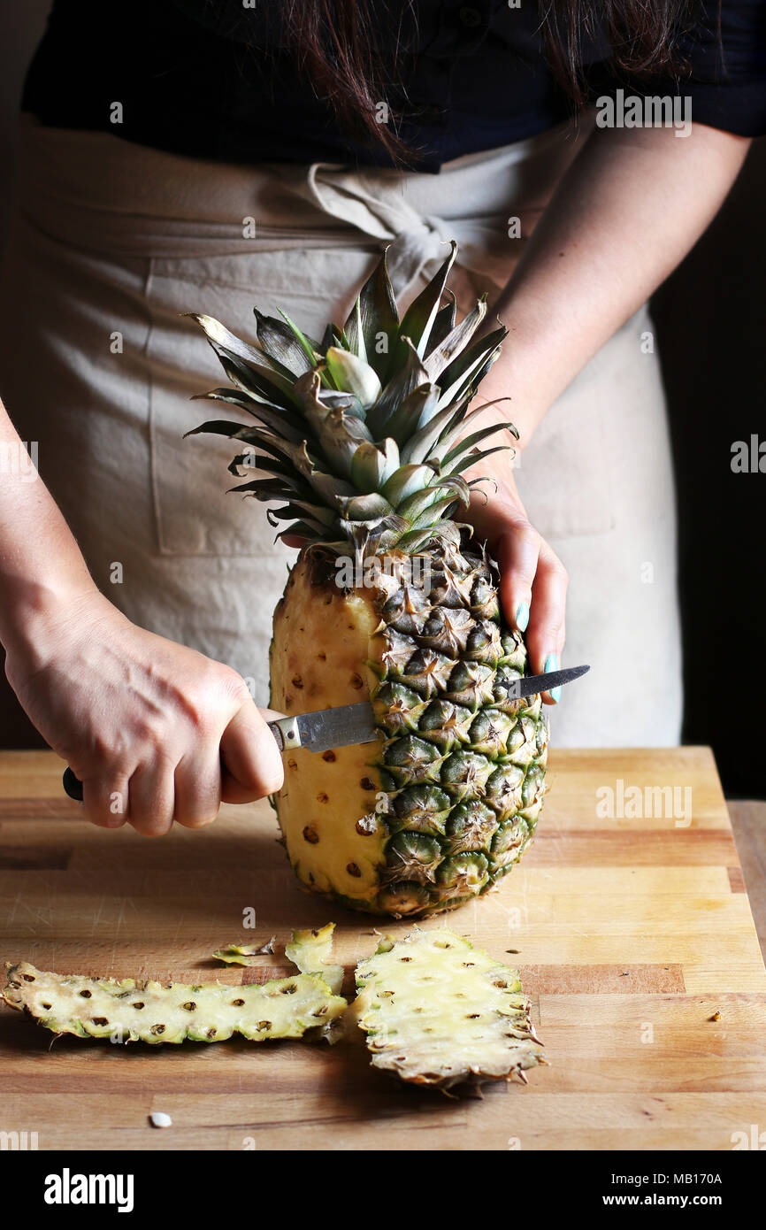 Taglio femminile un pinepple su una tavola di legno Foto Stock