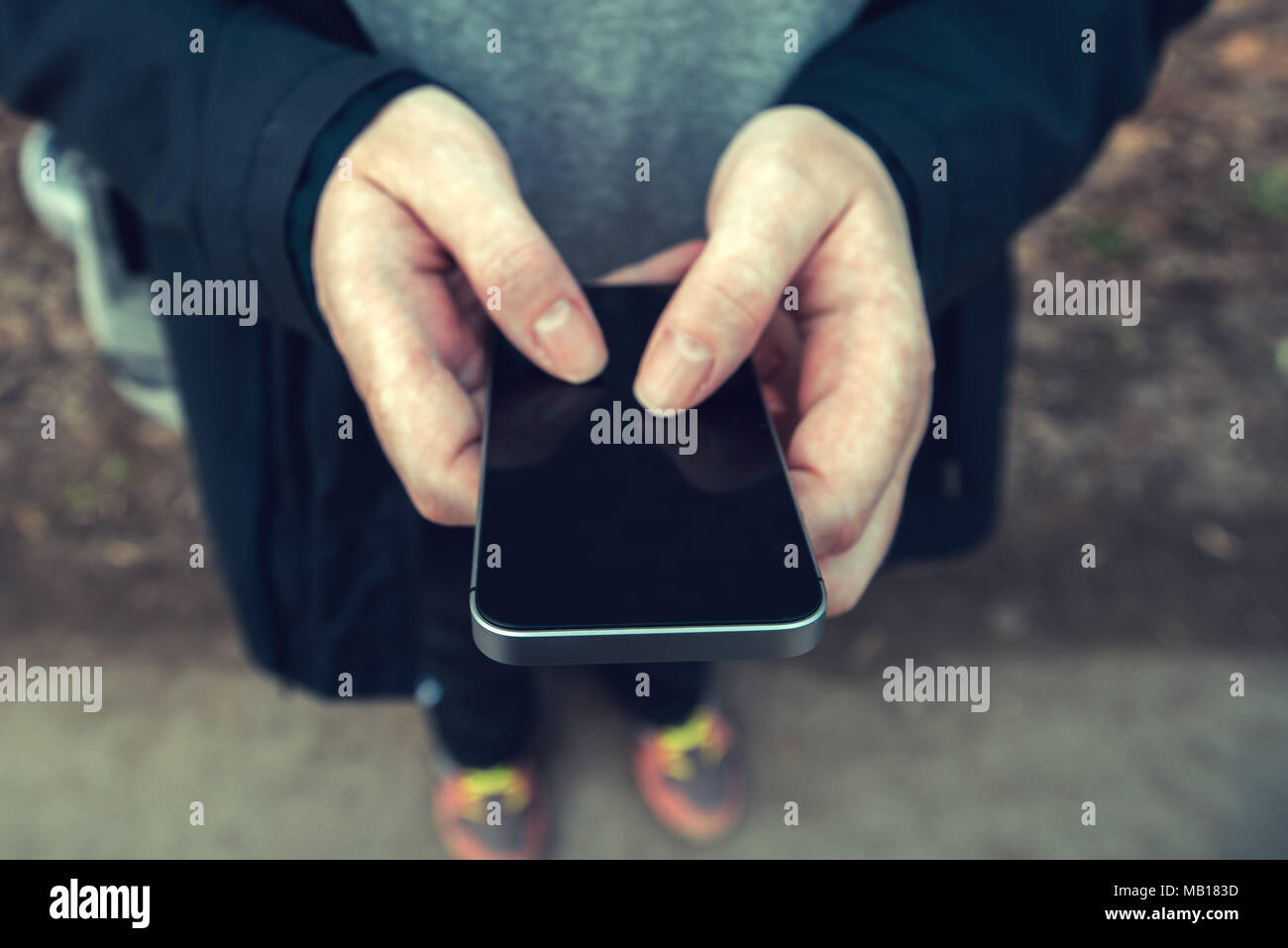 Close up di mani femminili utilizza lo smartphone all'aperto, ad alto angolo di visione con il fuoco selettivo Foto Stock