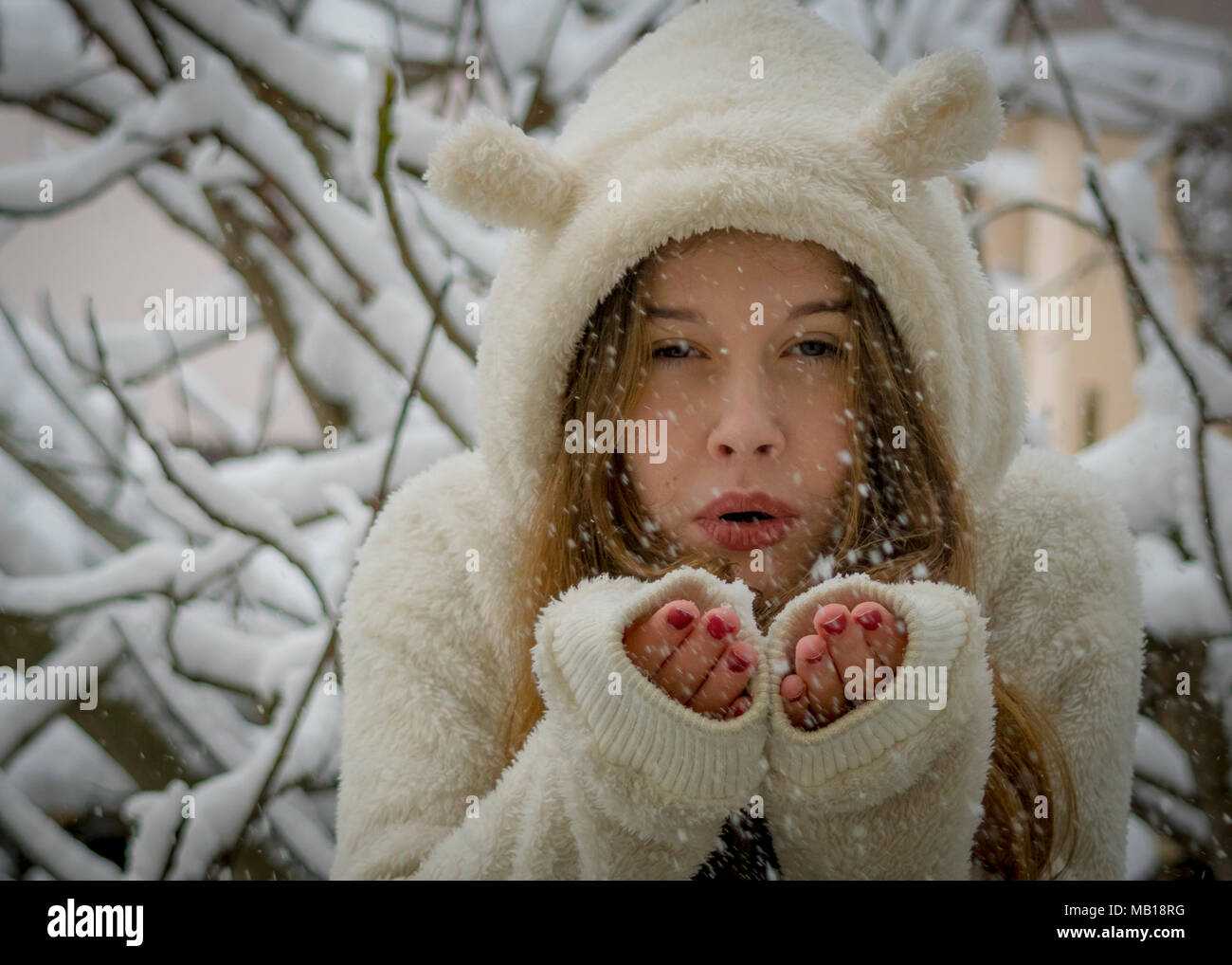 Ritratto di bella ragazza adolescente nella neve. Tema d'inverno. Primo piano della bocca, delle mani, colpi di fiocchi di neve nel vento. Godendo il freddo inverno nevoso. Foto Stock