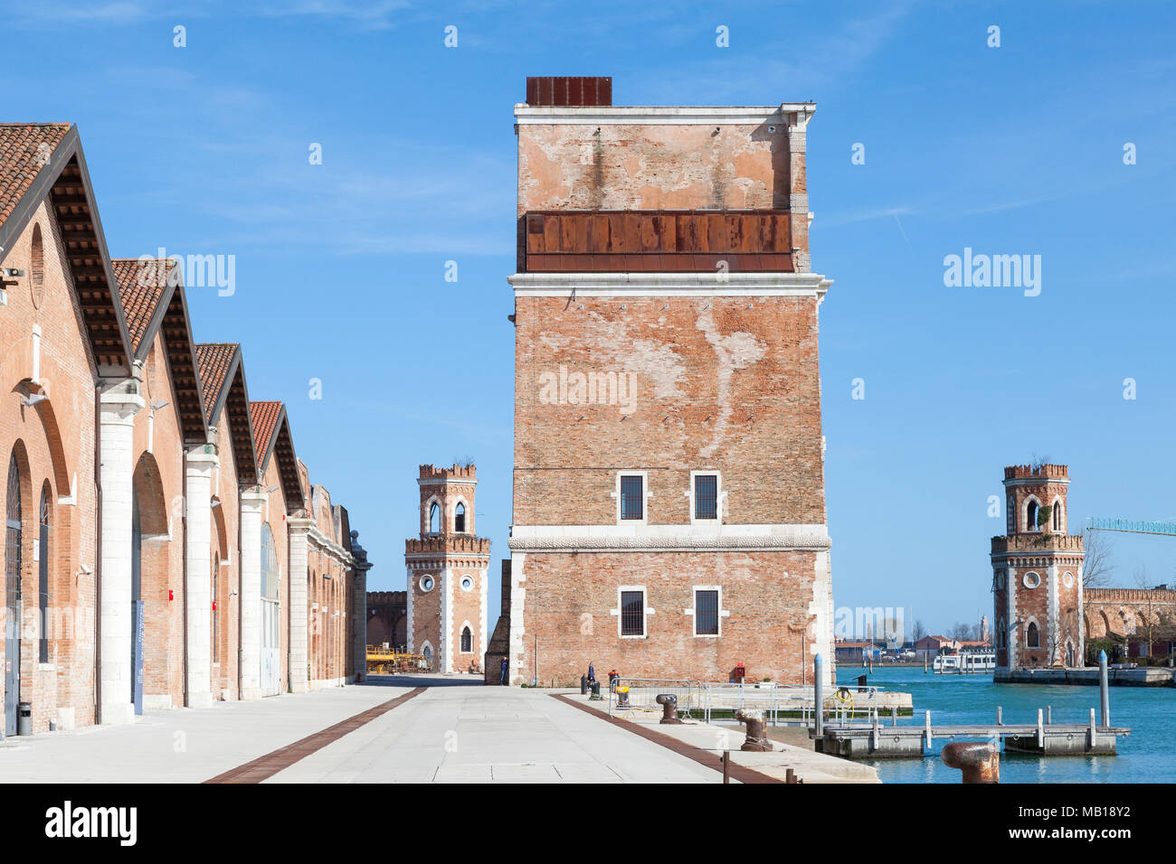 Il restaurato Porta Nova torre e due torri di controllo all'ingresso dell'acqua dell'Arsenale, Venezia, Veneto, Italia con vecchi magazzini boatbuilding ora Foto Stock
