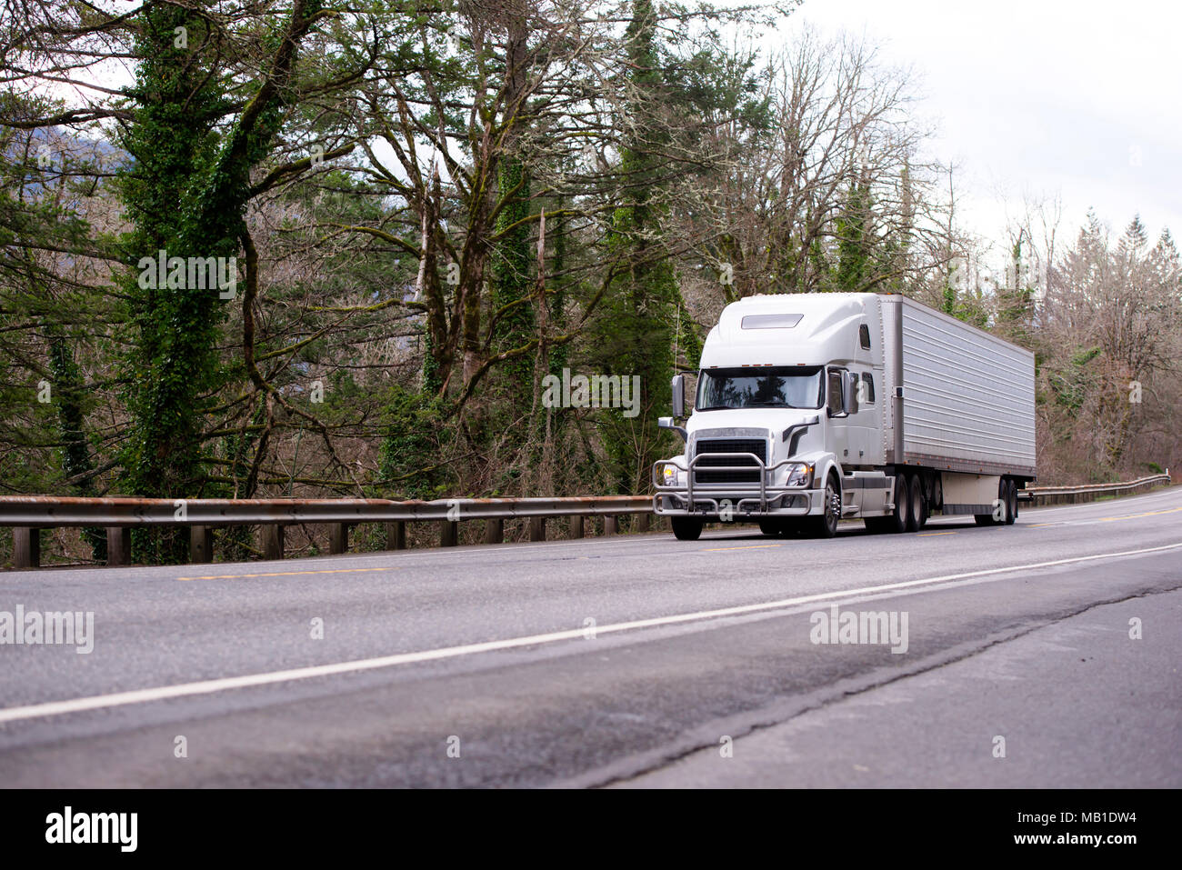 Bianca e moderna big rig semi carrello con protezione paraurti per protezione griglia il trasporto di refrigerare semi rimorchio con commerciale cargo sul desolato ro Foto Stock