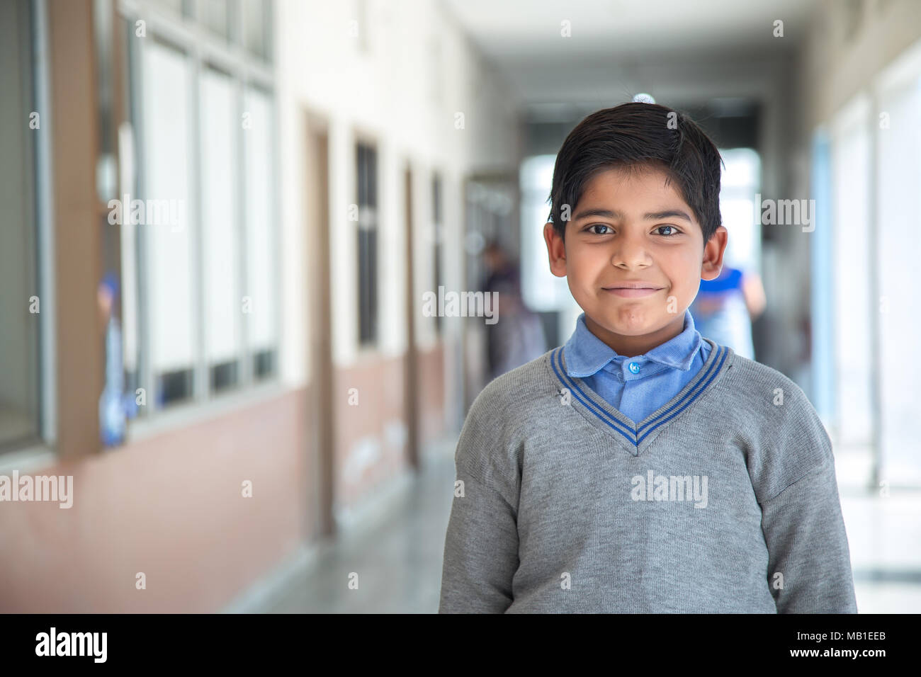 Closeup ritratto di sorridere 6-7 anni ragazzo indiano, dritto permanente presso il campus della scuola in uniforme scolastica e guardando la fotocamera Foto Stock