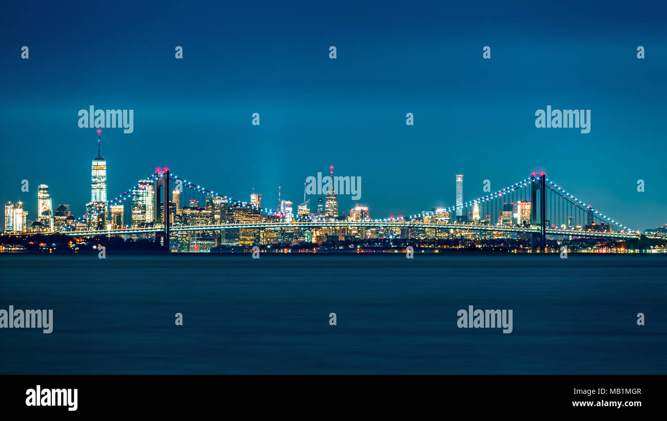 Verrazano Narrows Bridge cancelli di accesso superiore a New York Bay. Skyline di Manhattan sorge dietro il ponte. Foto Stock