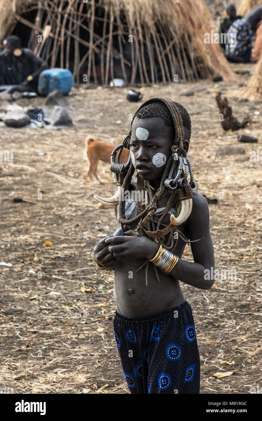 Omorate Etiopia - 24 Gennaio 2018: il bambino dalla tribù dei Mursi in posa per un ritratto nel suo villaggio con case tradizionali dei Mursi in Etiopia. Foto Stock