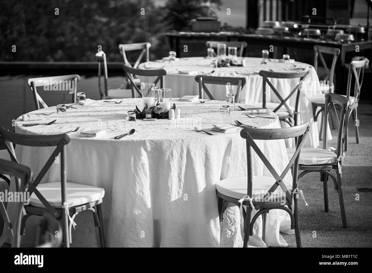 Il bianco e nero di ricevimento di nozze cena tabella configurazione, con il moderno prato pieghevoli sedie. Il bicchiere vuoto e mettere sul tavolo, la candela un Foto Stock