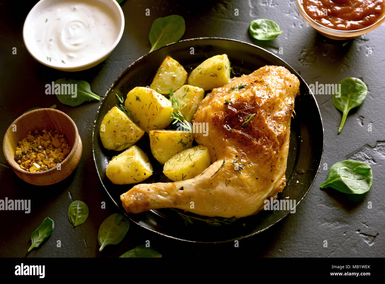 Pollo alla griglia della gamba con patate al forno su lastra in pietra nera tabella. Piatto per la cena. Foto Stock