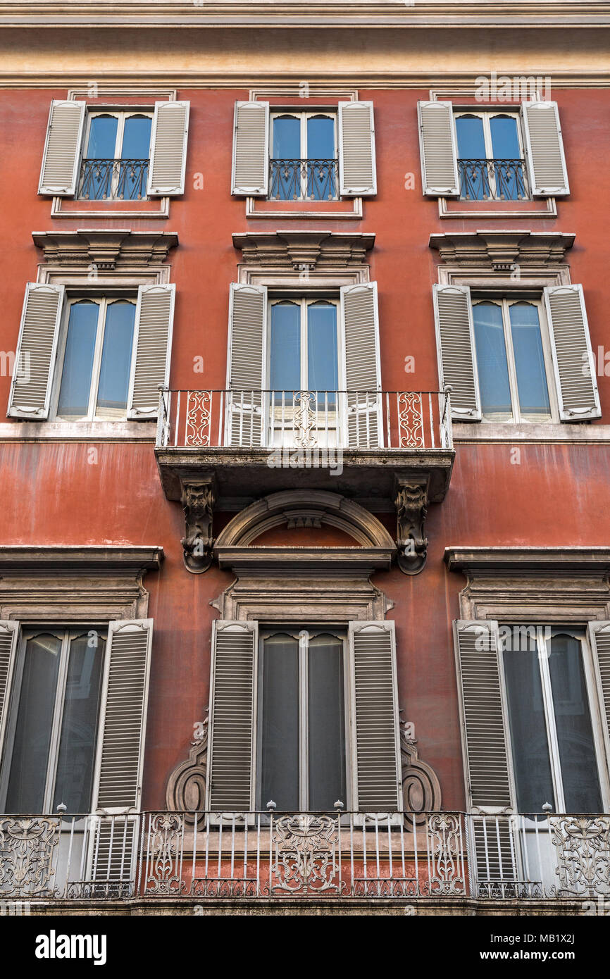 Guardando le pareti e le finestre di un vecchio edificio di appartamenti in Roma, Italia. Colore rosso intenso, spiovente con la patina della vita di città. Foto Stock