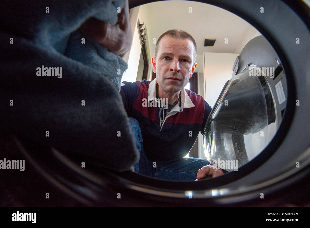 L'uomo il caricamento di una macchina di lavaggio, visto dall'interno del tamburo Foto Stock