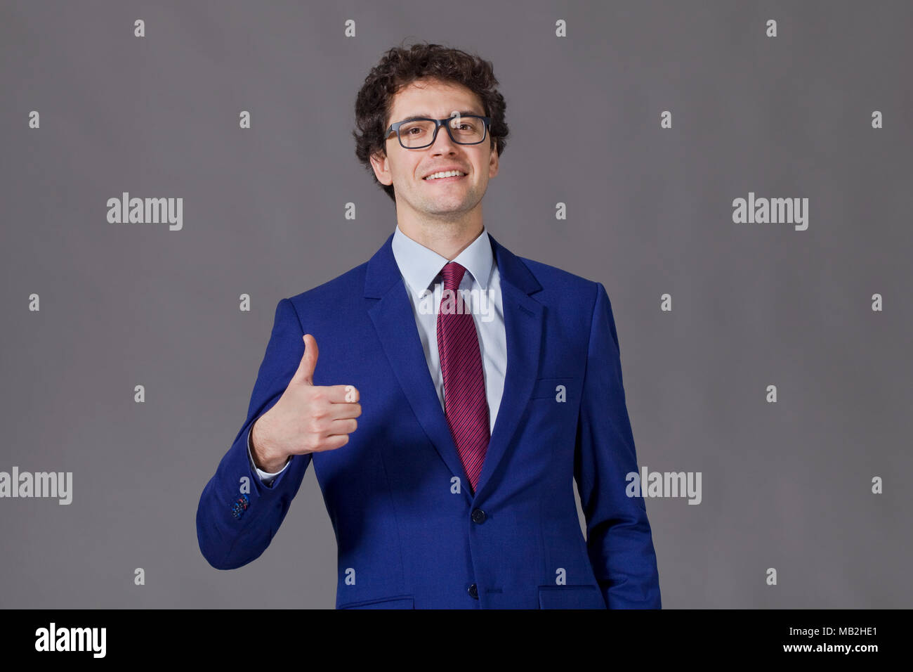Curly-headed boy sorridente e mostrando grande pollice in alto Foto Stock