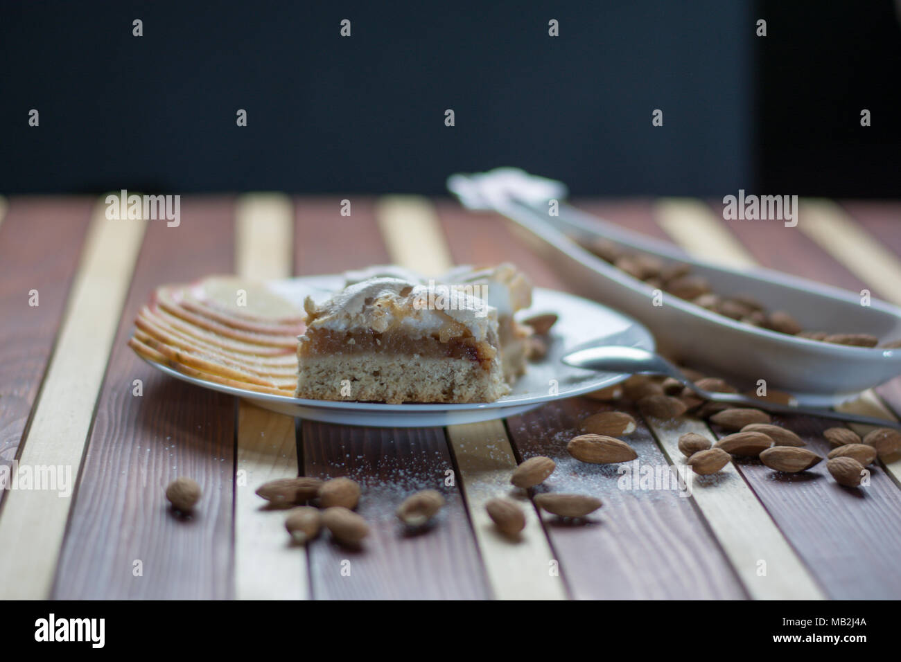 Forma quadrata omemade a fette di torta di mele con kumquat e mandorle su sfondo di legno Foto Stock