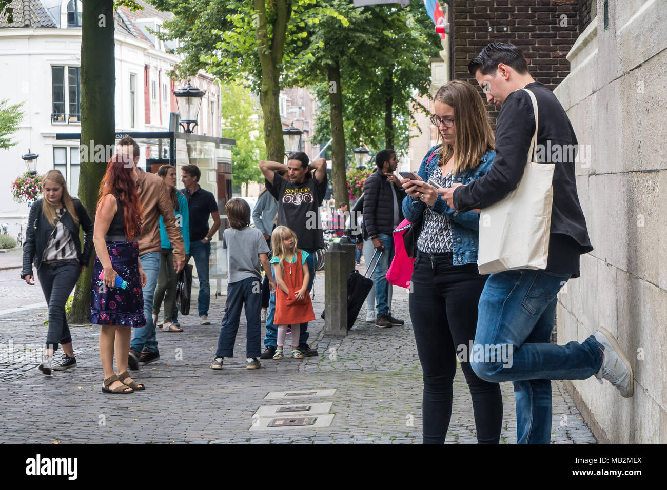 Utrecht, Paesi Bassi - 13 agosto 2016: coppia di turisti controllando il loro smartphone a una trafficata Piazza Dom. Foto Stock
