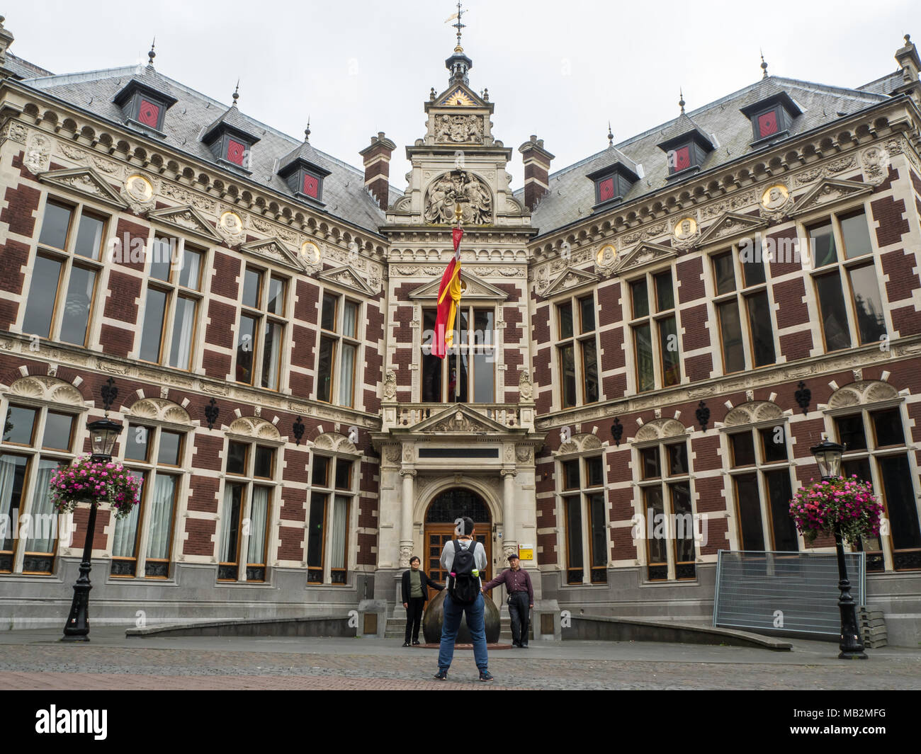 Utrecht, Paesi Bassi - 13 agosto 2016: turisti asiatici Scattare foto nella parte anteriore del palazzo dell'Accademia presso la Piazza Dom. Foto Stock