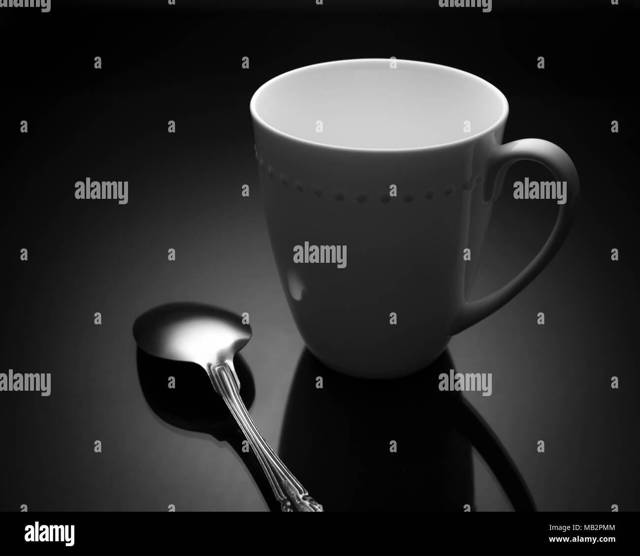 Caffè bianco tazza da tè con cucchiaio in metallo su sfondo nero in cucina Foto Stock