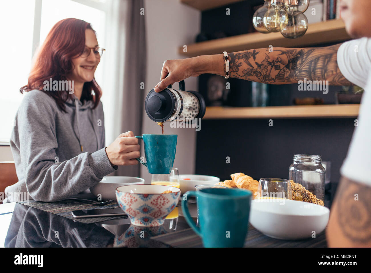 Bella donna di essere servito il caffè con la sua fidanzata in cucina. Amare giovane avente insieme per la prima colazione in mattina. Foto Stock