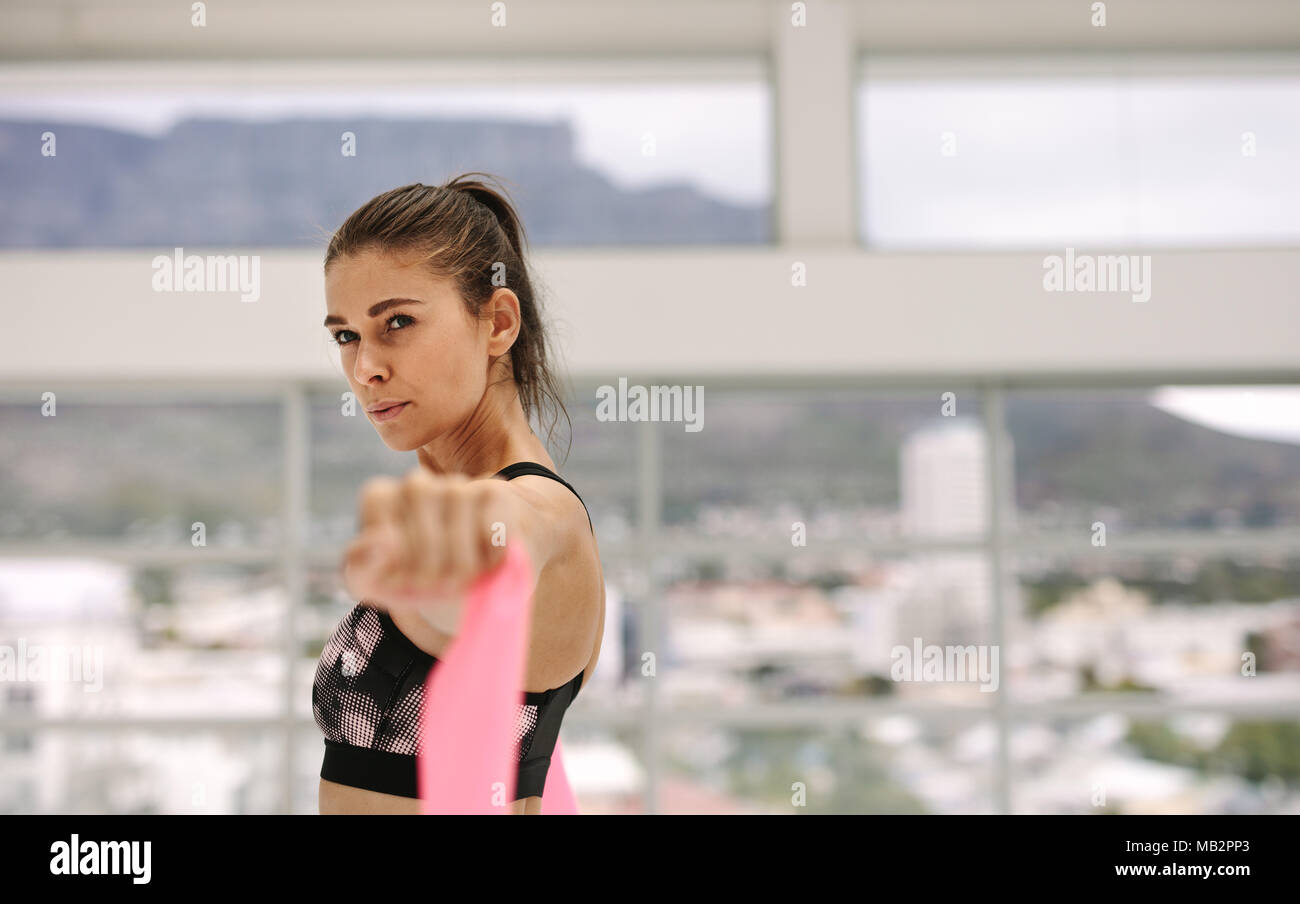 Donna difficili utilizzando una banda di resistenza in palestra. Esercizio femmina con banda di resistenza al fitness studio. Foto Stock