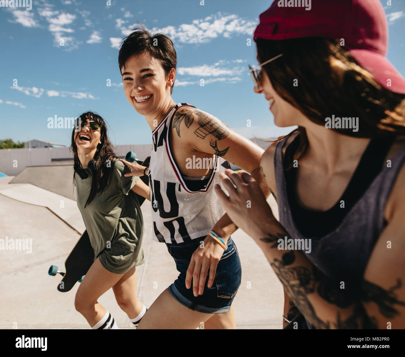 Il gruppo di donne amici correndo all'aperto a skate park. Pattinatori femmina godendo allo skate park. Foto Stock