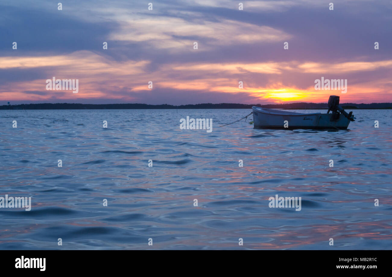 Singolo battello al tramonto, oscillare delicatamente nelle acque del suono. Appena fuori della Harkers Isola, North Carolina. La barca vi aspetta il pescatore Foto Stock