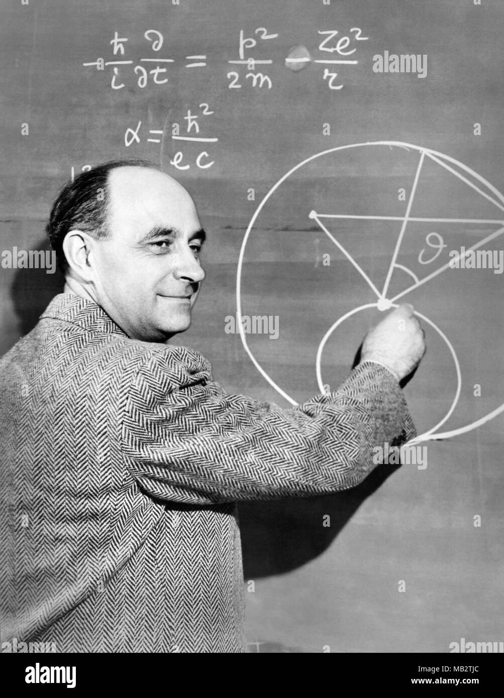 Enrico Fermi (1901-1954), fisico italo-americano e pioniere nel settore della fissione nucleare, demonstates una equazione di fisica su una lavagna, c1950. Fermi ha lavorato sul progetto Manhattan durante la II guerra mondiale e ha reso importanti contributi allo sviluppo della teoria quantistica, nucleare e della fisica delle particelle e la meccanica statistica. Foto Stock