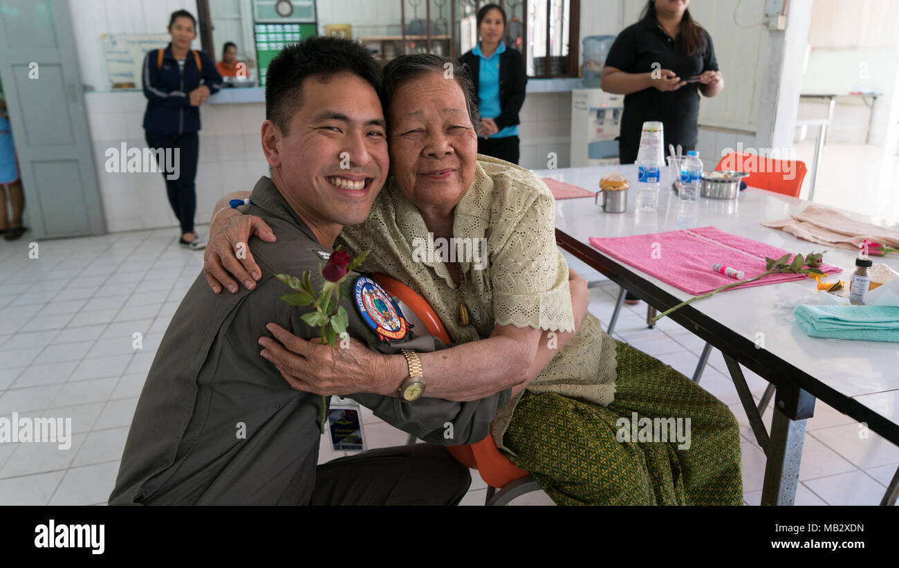 Royal Thai Air Force Flying Officer Pakorn Pisitsart abbracci un residente di Tam Ma Pa Korn (Watmuang) nursing home durante l'esercizio Cobra Gold 2018 in Korat, Regno di Thailandia, 14 febbraio, 2018. Pisitsart è un pilota con l'ala 1, Royal Thai Air Force. Umanitario assistenza civica programmi condotti durante il Cobra Oro 18 dimostrano un impegno reciproco per l'interesse umanitario di amici e nazioni partner, e mirano a migliorare la qualità della vita e la salute generale ed il benessere delle popolazioni civili residenti nelle aree di esercitazione. Cobra Gold 18 è un esercizio annuale condotta nel regno di Thail Foto Stock