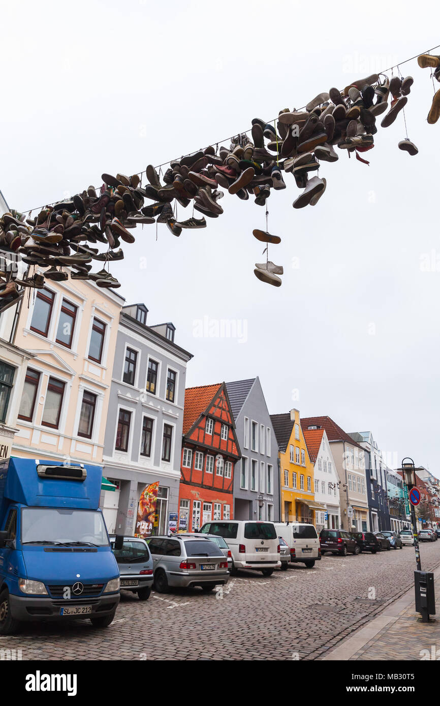 Flensburg, Germania - 10 Febbraio 2017: abbandonati scarpe sportive appendere sul filo elettrico su strada urbana, Street View di vecchi Flensburg, Germania. In verticale Foto Stock