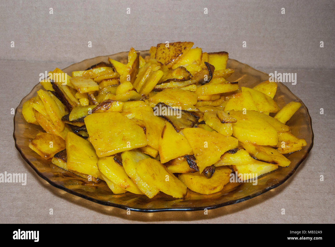 Patate fritte, condito con la curcuma, giacciono su una piastra. Un paese caldo pasto. Foto Stock