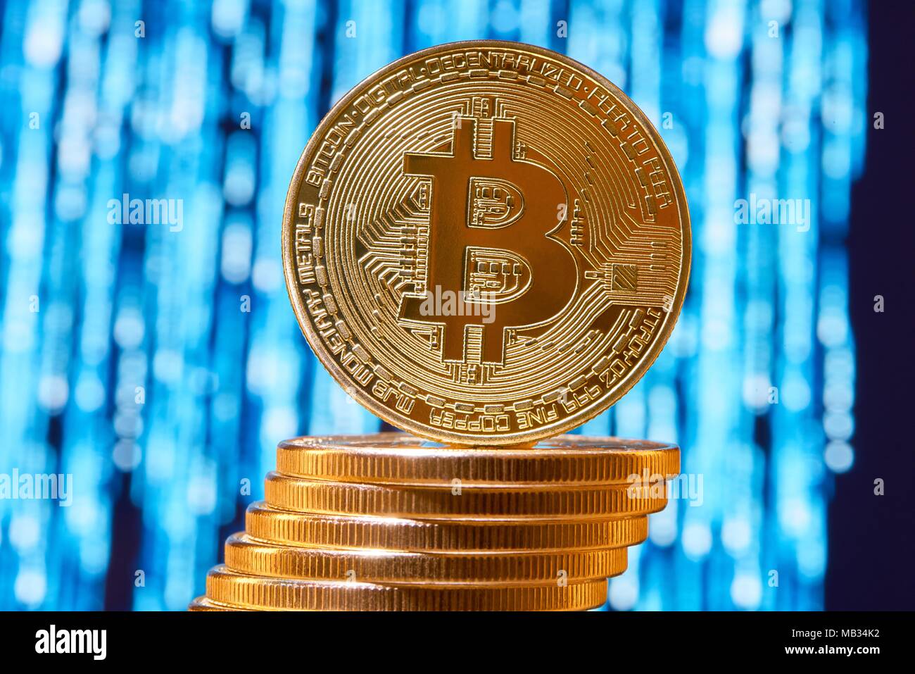 Uno bitcoin sul bordo posto sulla pila di golden bitcoins sfocata circuito blu su sfondo. Digital denaro virtuale valuta elettronica blockchain stock exchange futuro finanziamento bancario innovativi Foto Stock