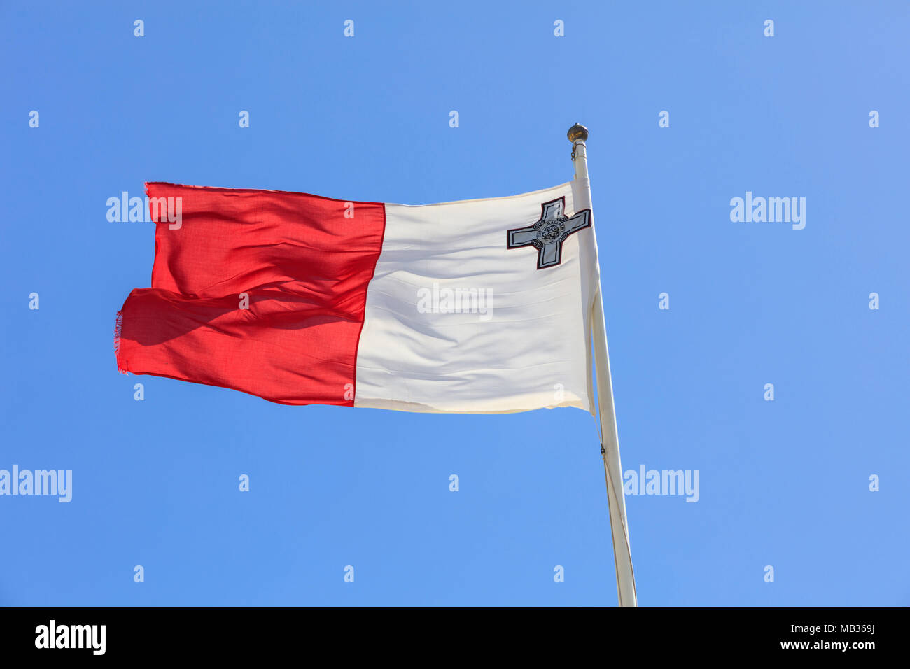 Bandiera di Malta. Bandiera di Malta su un pennone sventolando in direzione opposta su un cielo blu sullo sfondo Foto Stock