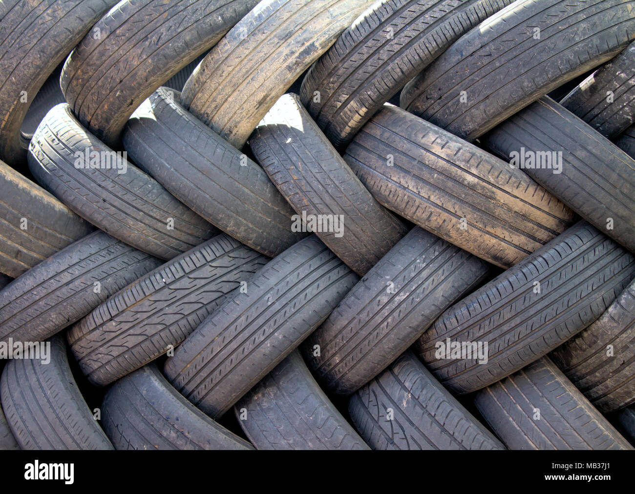 Parete di usurati di pneumatici vettura in attesa di smaltimento per un centro di riciclaggio. Foto Stock