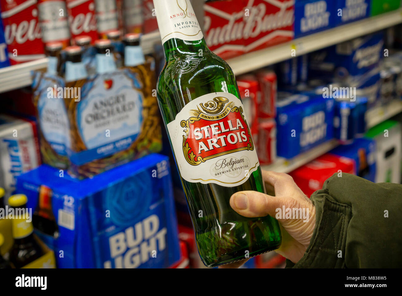 Un cliente sceglie una bottiglia di Stella Artois birra in un supermercato raffreddatore in New York Martedì, 3 aprile 2018. Stella Artois recentemente ricordato alcuni dei suoi 11,2 oncia di bottiglie a causa della possibilità che potrebbero contenere piccoli pezzi di vetro. Stella Artois è un marchio della mega-birraio Anheuser Busch InBev SA. (© Richard B. Levine) Foto Stock