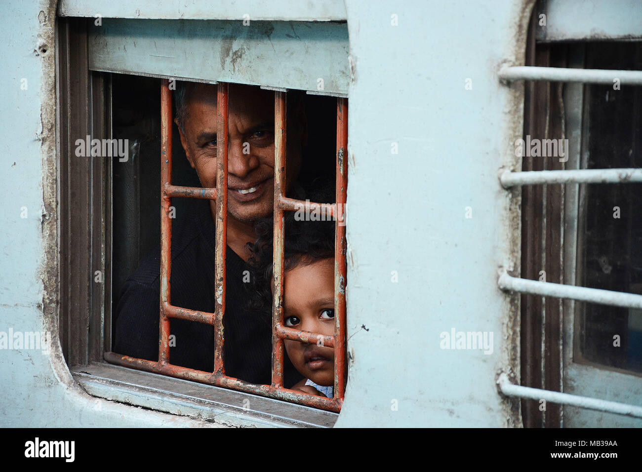 Uomo e bambino sul passaggio di un treno indiano Foto Stock