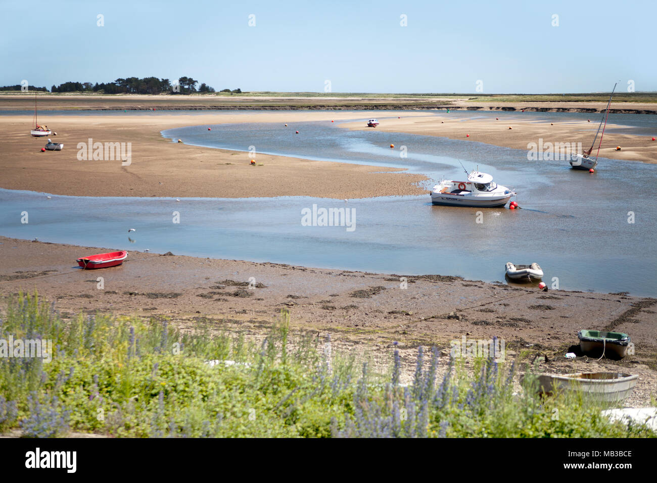 Una vista dalla strada della spiaggia, Pozzi-next-Mare, Norfolk, con la bassa marea, guardando verso Est Flotta estuario, con spiaggiata barche e boe Foto Stock
