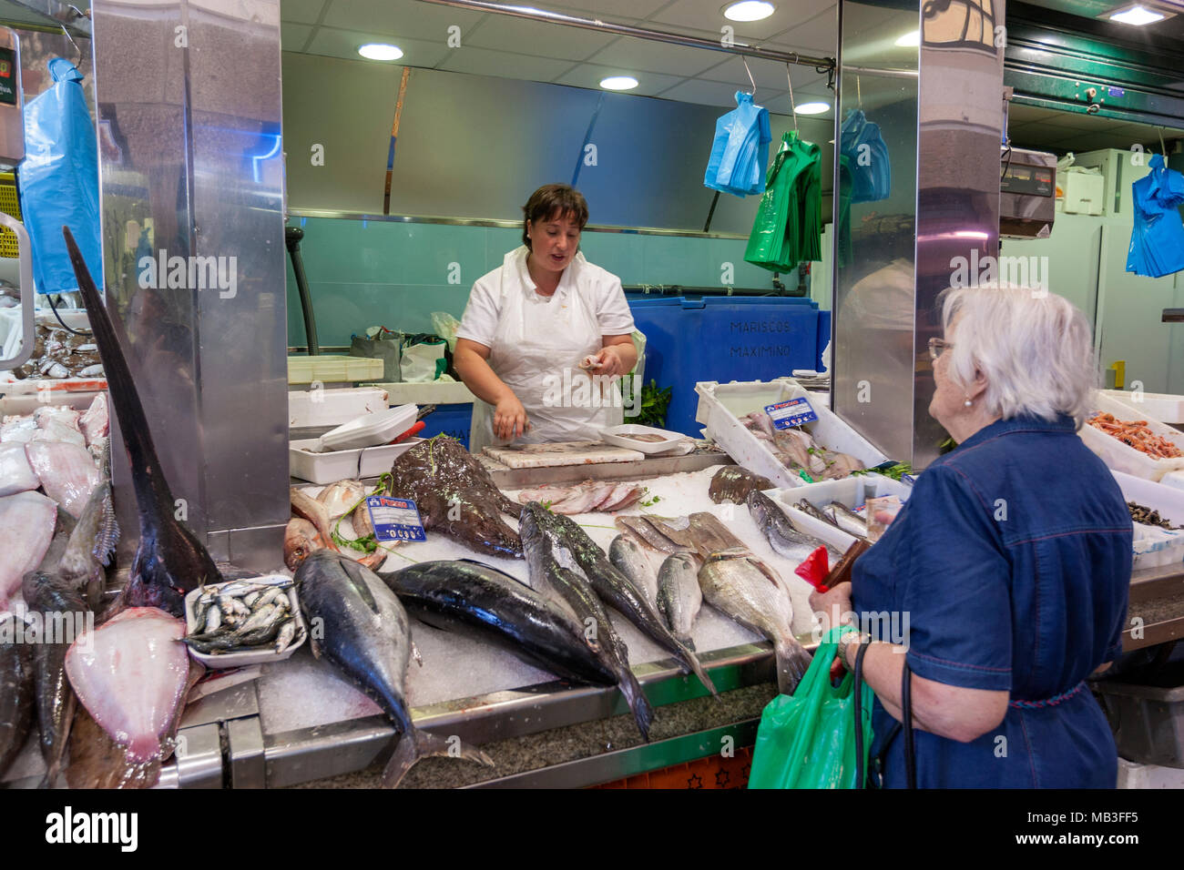 Pescivendolo nel tradizionale indoor/outdoor mercato con bancarelle del fornitore del Mercado de Abastos de Santiago de Santiago de Compostela, Galizia, Spagna Foto Stock