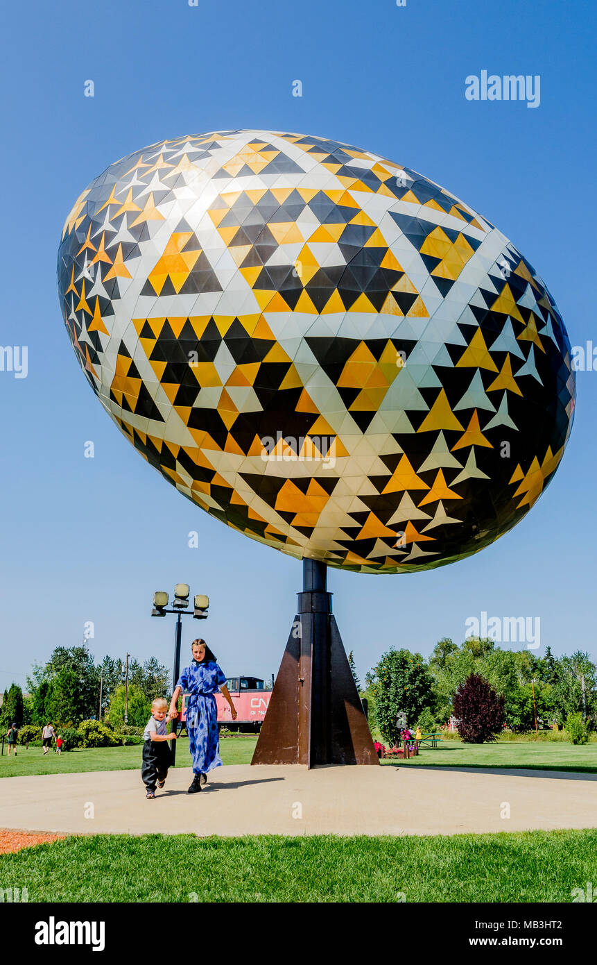 Mennonita bambini all'uovo Vegreville, una gigantesca scultura di un pysanka, un stile ucraino uovo di Pasqua. È il più grande pysanka nel mondo. Vegrev Foto Stock