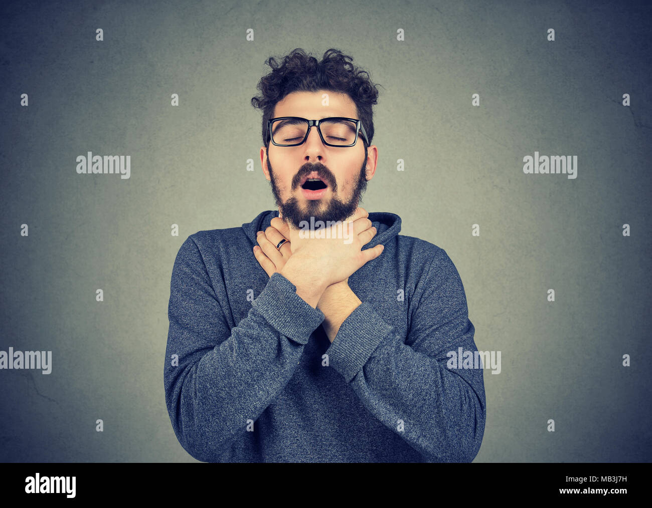 Giovane uomo avente attacchi di asma o parzializzando impossibile respirare Foto Stock