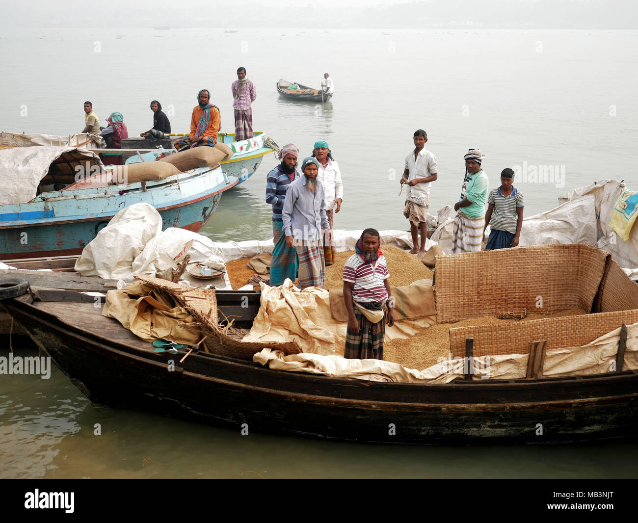 Gli equipaggi delle imbarcazioni il trasporto di riso. Nel delta dei fiumi Ganga (Padma), Brahmaputra e Meghna persone vivono sull'acqua. Area intorno al paese Banaripara è allagato con acqua. Le persone vivono in villaggi sulle rive dei canali del fiume. No il trasporto su strada è possibile. Solo acqua e le navi che li collegano con il resto del mondo. Ma la zona è molto vivace. Gli agricoltori coltivano frutta e verdura, il riso e le colture su 2 700 chilometri quadrati di territorio tra il fiume canali. I fornitori visita il loro cliente su barche. Mercati galleggianti con verdura, frutta, di riso o di legname sono comuni in questo settore. Le persone a costruire navi Foto Stock