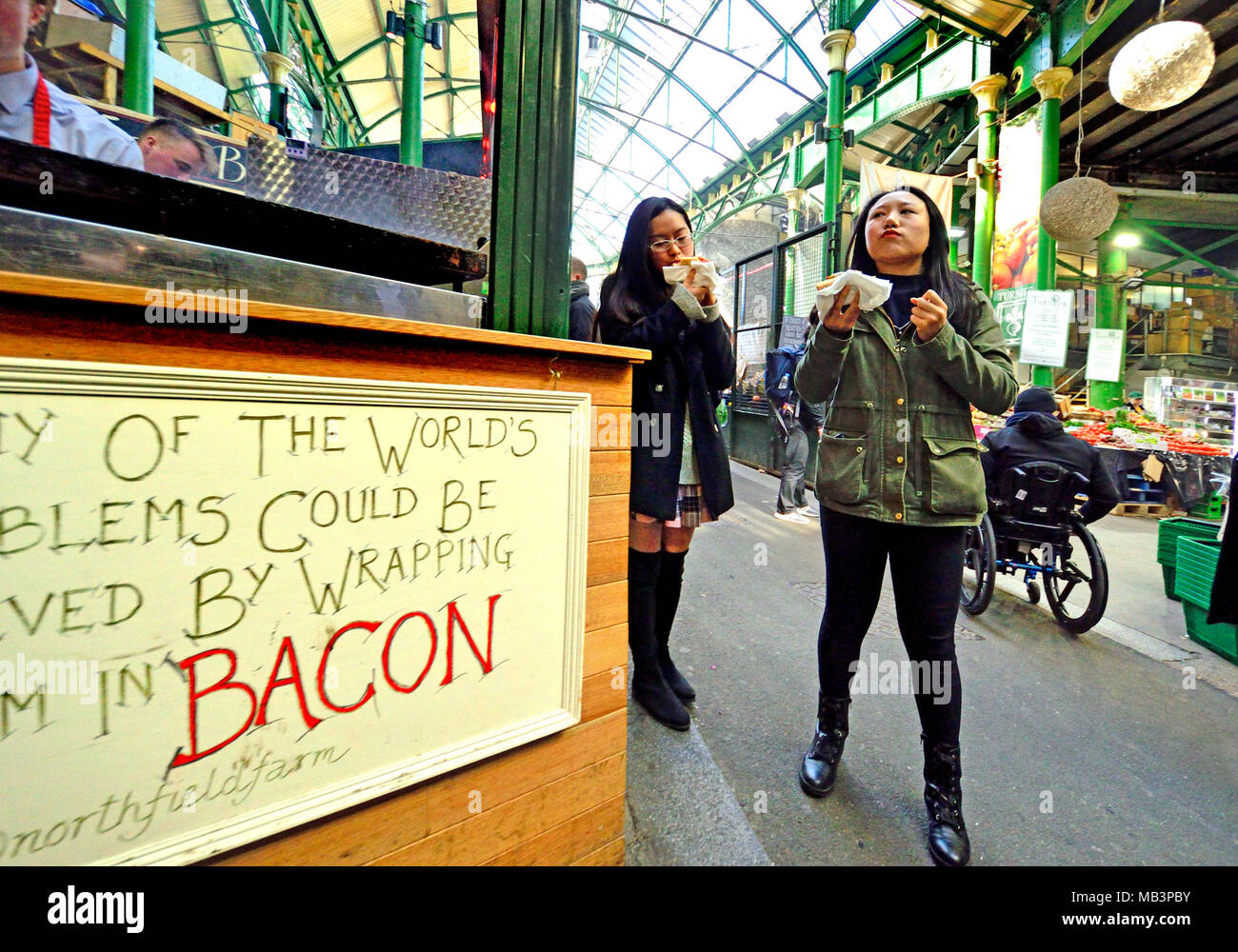 Londra, Inghilterra, Regno Unito. Due donne giapponesi strada mangiando cibo nel mercato di Borough, Southwark Foto Stock