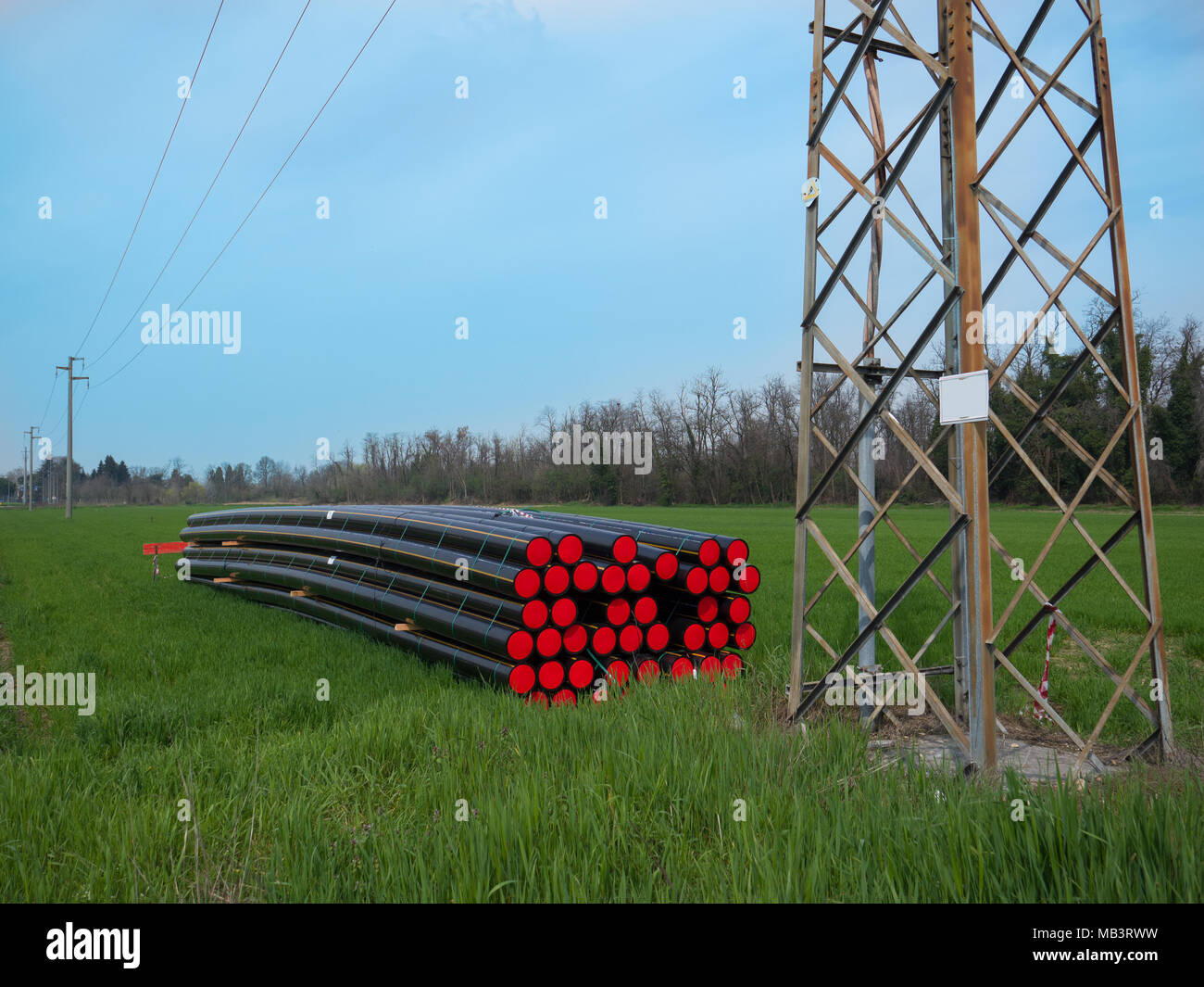 Pila di tubi colorati giacente in un prato in attesa di essere utilizzati Foto Stock