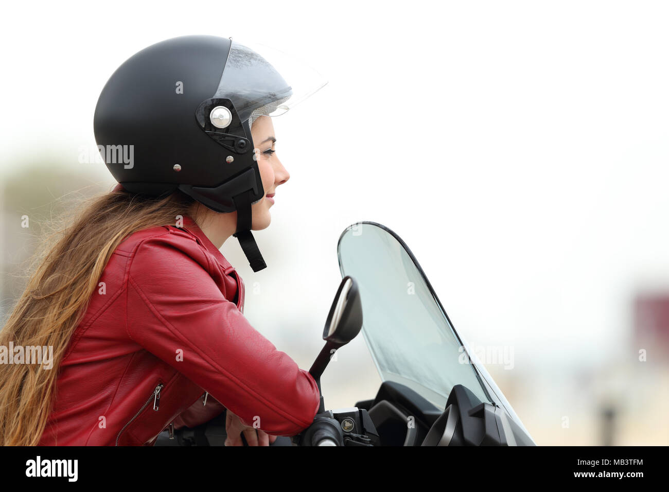 Vista laterale di un soddisfatto biker guardando lontano su una moto Foto Stock