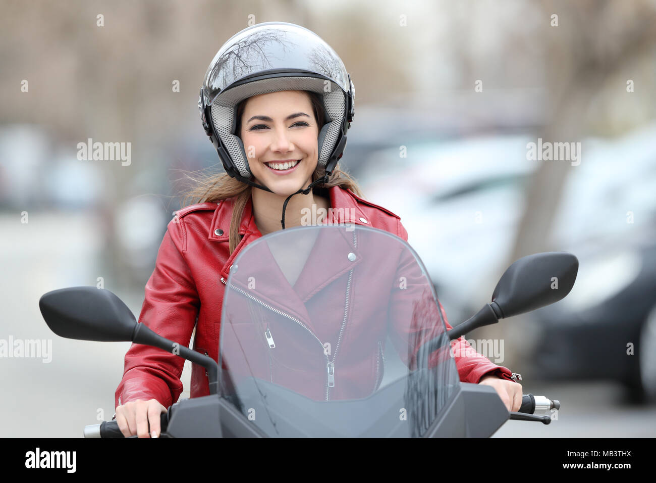 Vista frontale il ritratto di una donna felice la guida uno scooter su strada Foto Stock