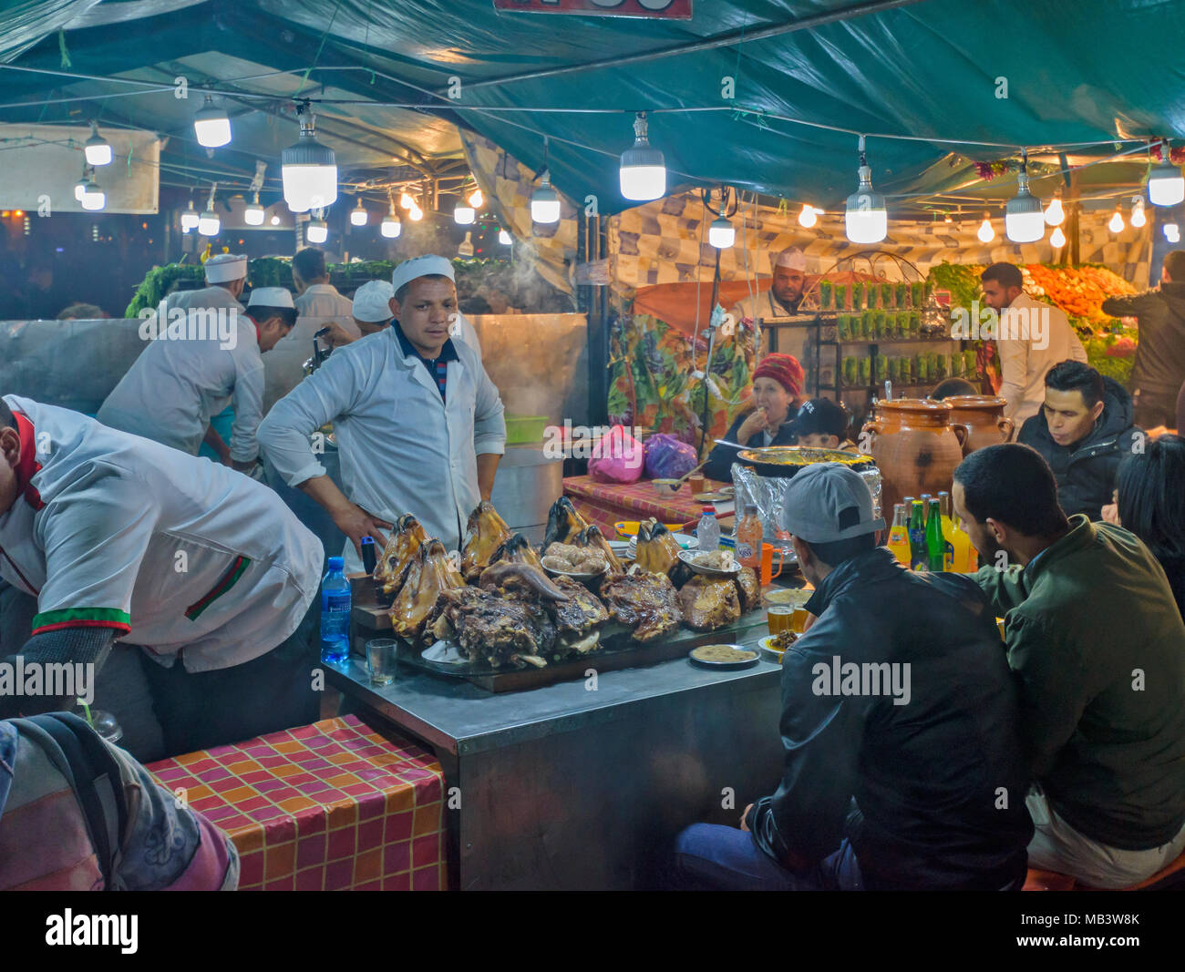Il Marocco Marrakech Jemaa el Fna MEDINA SOUK sera nella piazza di bancarelle che vendono una vasta gamma di cibi cotti dove è possibile sedersi e mangiare cucinato capi di ovini Foto Stock