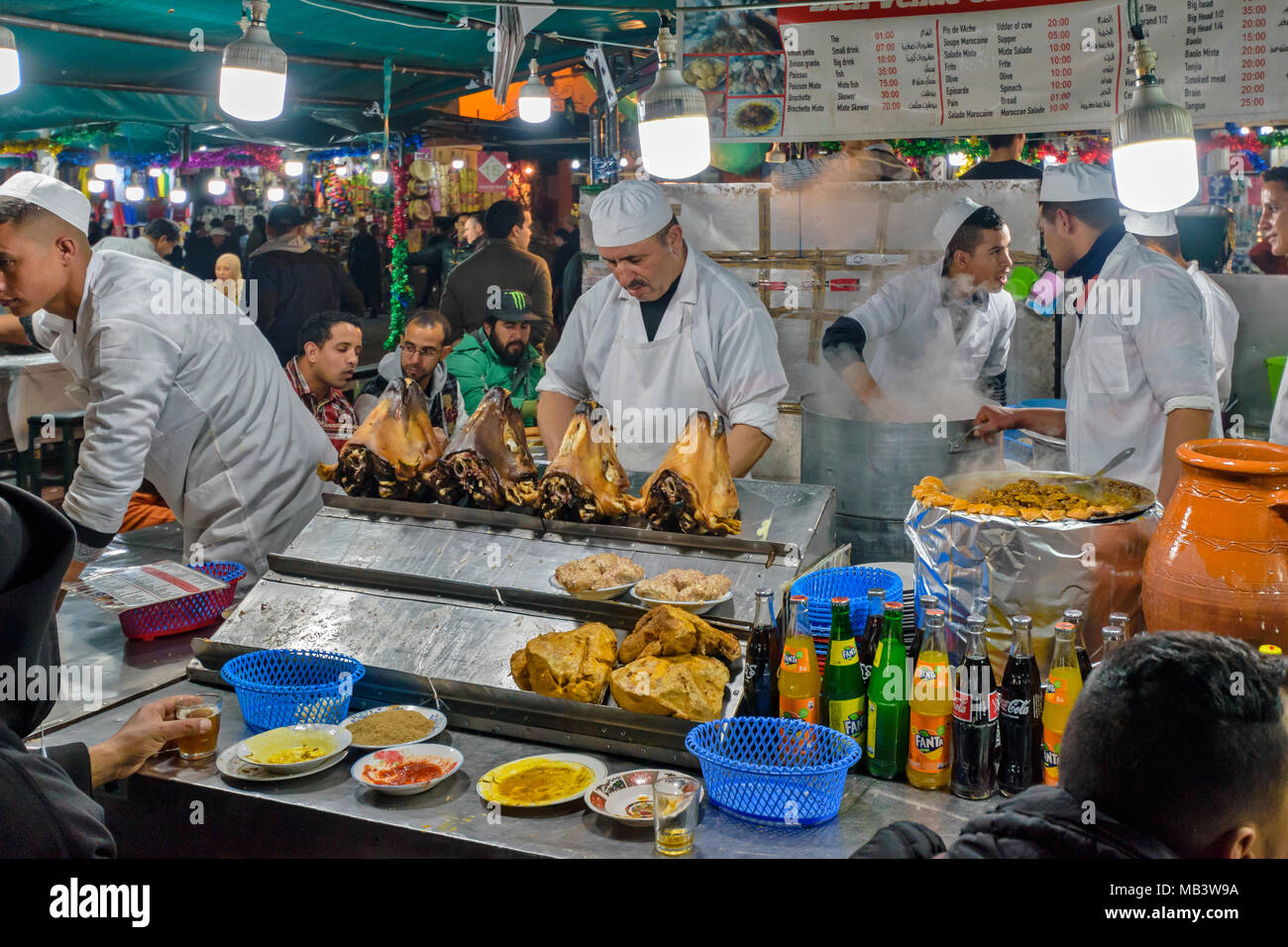 Il Marocco Marrakech Jemaa el Fna MEDINA SOUK sera nella piazza di bancarelle che vendono una vasta gamma di cibi cotti dove è possibile sedersi e mangiare cucinato capi di ovini Foto Stock