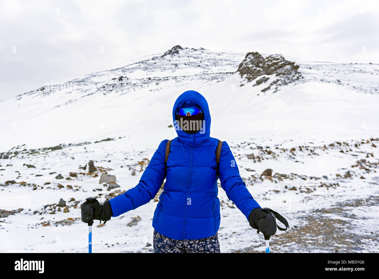 Ragazza scalatore o sciatore in vestiti caldi, antivento maschera e occhiali antivento in montagne invernali Foto Stock