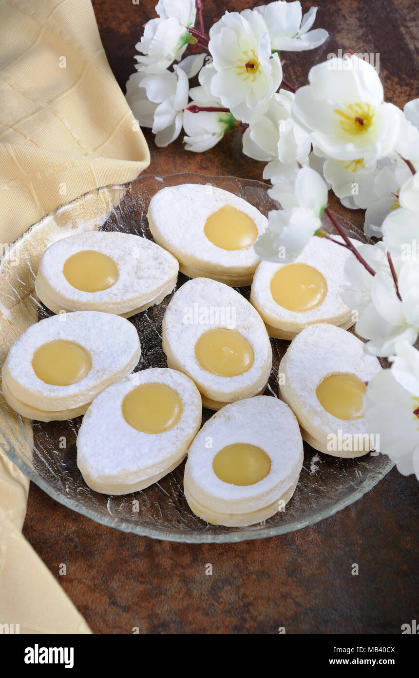 Un delicato, la fusione in bocca a casa biscotto di Pasqua realizzata dalla sabbia nella forma di un uovo con un riempimento di un limone curda cosparso con pow Foto Stock